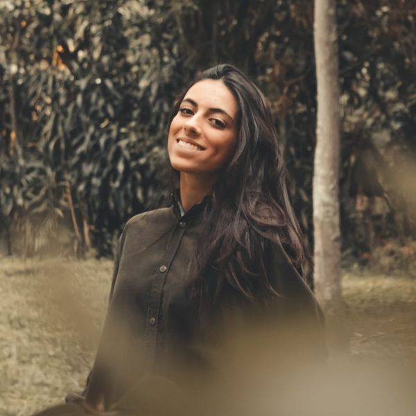Person smiling and looking refreshed outdoors with natural light.
